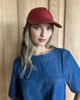 Gorra tipo visera confeccionada en cuero con textura de pelo, diseño clásico con ojales metálicos de ventilación y ajuste posterior.