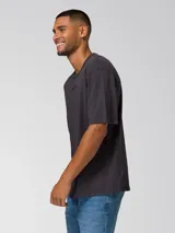 Remera de manga corta color gris oscuro con efecto lavado, cuello redondo y logo bordado en el pecho. Cuenta con un parche tejido en la manga.
