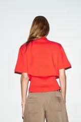 Top de punto liso color rojo, con cuello subido, manga corta con hombreras y bajo acabado en rib.