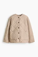 Campera acolchada de color beige con diseño guateado en rombos, hombros caídos, cuello redondo, cierre frontal de botones y bolsillos parche delanteros. Incluye una bufanda a juego que se abrocha en la nuca y cuenta con aislamiento térmico THERMOLITE.