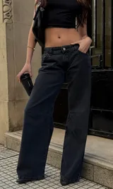 Jeans wide leg de denim rígido, tiro bajo y color negro.