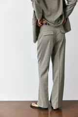 Pantalón de tiro alto color negro, de corte recto y pinzas frontales. Incluye un cinturón delgado de cuero marrón con hebilla metálica dorada.