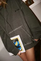 Buzo hoodie de algodón color gris oscuro con efecto lavado, calce oversized, capucha, bolsillo canguro frontal y pequeño estampado en el pecho.