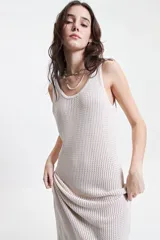 Vestido largo de punto con textura acanalada, escote redondo y tirantes anchos. Presenta una silueta ajustada al cuerpo y un tajo lateral en la parte inferior.