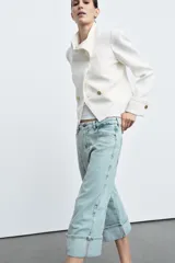 Jeans capri de tiro medio con cintura con trabillas y cinco bolsillos. Presenta pespuntes marcados a contraste y bajo acabado en vuelta.