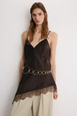 Top lencero de tejido satinado color marrón oscuro, con escote en V y tirantes finos ajustables. El bajo es asimétrico y está adornado con encaje a tono.
