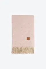 Pashmina de textura suave en color rosado, decorada con pequeñas perlas aplicadas en toda la superficie. Presenta flecos en los extremos y un parche de cuero sintético con logo grabado.