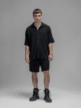 Camisa de corte oversize color negro, confeccionada en lino, con cuello tipo cubano, cierre frontal de botones y mangas cortas.