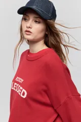Sweater de punto marrón de tejido liviano y calce relajado, con hombros caídos, cuello redondo y puños y cintura en rib. Cuenta con una estampa tejida en el frente con la frase "Estoy Blessed" en color amarillo.