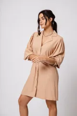 Vestido corto color tostado, con cuello solapa, abotonado al frente y mangas 3/4 con puños fruncidos.