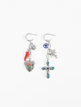 Par de caravanas asimétricas de estilo colgante con base de argolla plateada. Un pendiente presenta dijes de estrella, ají rojo y corazón con rosa esmaltada; el otro incluye dijes de ojo turco, ángel y cruz con piedras de cristal azul.