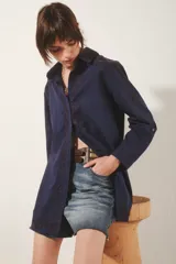 Camisa de corte amplio en color azul marino, con cuello clásico y cierre frontal de botones. Presenta delicados bordados florales tono sobre tono en el frente, mangas y espalda. Las mangas largas incluyen presillas internas para ajustar su largo.