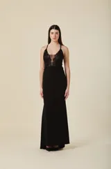 Vestido largo negro de gala con escote profundo y detalles de encaje bordado en el torso. Presenta breteles finos y una falda de corte recto con caída fluida.