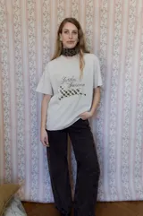 Remera de algodón color beige con estampa frontal que incluye la frase 'Jardín de Invierno' y un diseño gráfico de un animal con patrón de cuadros.