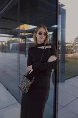 Vestido negro de largo midi, confeccionado en tejido grueso con efecto ante. Presenta mangas largas, escote con abertura en el pecho, cintura elastizada con frunces, tajo lateral y cuello medio alto.