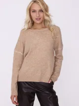 Sweater color beige de tejido de punto con cuello redondo y mangas largas con detalle de costuras blancas en los hombros.