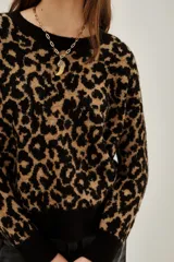 Sweater de punto con estampado animal print en tonos negro y tostado, de cuello redondo y mangas largas con puños acanalados.