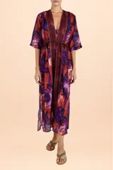 Cover up largo tipo túnica con escote en V, mangas tres cuartos y lazo ajustable en la cintura. Presenta un estampado vibrante de hojas en tonos púrpuras y cobrizos con detalles geométricos en los bordes frontales.