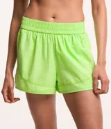 Short deportivo tipo runner para mujer, color verde lima fluorescente, con textura de pequeños agujeros (malla). Presenta cintura elástica funcional y un forro interior que asoma en el ruedo redondeado.