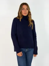 Sweater de punto color azul marino, con cuello alto, manga larga y puños acanalados. Presenta una costura vertical decorativa en el centro del frente y un ruedo acanalado con terminación asimétrica.