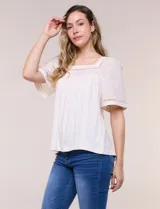 Blusa de corte holgado color marfil, confeccionada en mezcla de modal y algodón, con escote cuadrado y mangas cortas adornadas con detalles de puntilla calada.