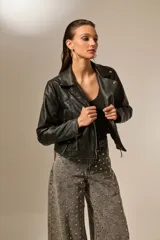 Campera de cuero sintético negra, con cuello solapa, cierre asimétrico con cremallera, bolsillos laterales con cremallera y corte entallado.