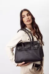 Cartera de mano estructurada de cuero vacuno rojo, con doble asa superior y detalles de charol en la parte superior. Cuenta con cierres metálicos y apliques decorativos laterales con hebillas.