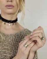 Gargantilla tipo choker de gamuza con dijes colgantes artesanales de metal y perlas naturales. Cuenta con tiras largas para atar y ajustar en la parte posterior.