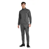 Conjunto deportivo Under Armour para hombre, compuesto por una campera con cierre frontal y cuello alto, y un pantalón de corte ajustado. Ambas piezas presentan el logo de la marca en color negro y franjas laterales oscuras.