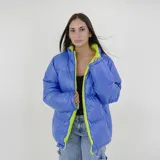 Campera puffer reversible de corte holgado, con cuello alto y cierre frontal. Un lado es de color azul vibrante y el otro es de color verde lima, ambos con acabado brillante.