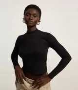 Remera blanca de algodón con cuello alto y mangas largas. Diseño ajustado al cuerpo y textura acanalada.