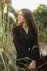 Blazer de gamuza color marrón oscuro, con solapas de muesca, cierre frontal de dos botones grandes claros y bolsillos frontales ribeteados.