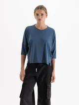 Remera de silueta relajada confeccionada en tela de punto suave, con escote redondo, mangas 3/4 y tajos laterales que aportan movimiento.