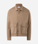Sobrecamisa de sarga de algodón en color beige, de corte amplio y estructurado, con cuello camisero, mangas largas, cierre frontal de botones ocultos y grandes bolsillos frontales con solapa.