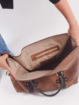 Bolso de viaje tipo duffle, confeccionado en cuero natural color azul con textura, con detalles de correas y asas en cuero color suela. Cuenta con cierre superior, bolsillo interior con cierre y compartimento para celular.
