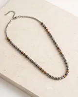 Collar masculino confeccionado con cuentas cilíndricas de acero y piedras naturales en tonos marrones y plateados.
