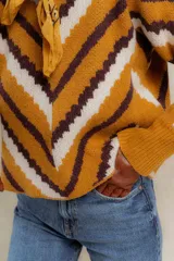 Sweater de punto jacquard con diseño de chevron en tonos celeste y marrón. Presenta cuello redondo, corte holgado y mangas largas con hombros abullonados.