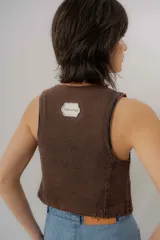 Chaleco de denim azul con cuello en V, cierre frontal con botones metálicos y pespuntes en contraste.