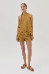 Short de guipur floreado color mostaza, confeccionado en tela especial que aporta textura y sofisticación.