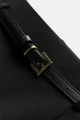 Pantalón culotte negro de tiro medio con trabillas y cinturón fino efecto piel con hebilla metálica. Presenta raya planchada y cierre de cremallera oculta en la costura.