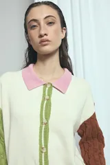 Cardigan de punto color marrón, con cuello vuelto, cierre frontal de botones y detalles de ribetes a rayas en los puños, la cintura y la botonera. Las mangas presentan un diseño tejido en relieve con textura de ochos.