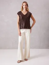 Blusa sin mangas con escote en V, confeccionada completamente en lentejuelas color dorado. Cuenta con forro interno a tono y un corte recto y holgado.