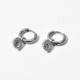 Par de aros plateados tipo argolla con dije colgante circular con diseño calado.