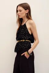 Top halter negro con detalles metalizados dorados, escote fruncido con tirantes finos y lazo ajustable al frente.