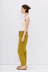Pantalón tipo babucha de tiro alto, color verde mostaza, confeccionado en símil lino. Presenta cintura elastizada con lazo de ajuste y largo al tobillo.