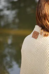 Poncho tejido en lana merino color marrón, con diseño de punto acanalado y terminación con flecos en el borde inferior. Incluye una pequeña etiqueta de cuero en la parte posterior.