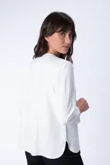 Blusa blanca de manga larga con cuello mao y cierre frontal con botones.