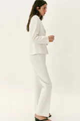 Blazer entallado color blanco de cuello sin solapa, manga larga con hombreras, falsos bolsillos delanteros de vivo y cierre frontal con un botón.
