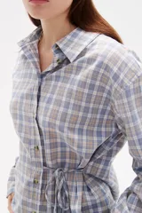 Camisa de poliéster con estampado a cuadros, cuello camisero, cierre frontal con botones y detalle de lazo ajustable en la cintura.