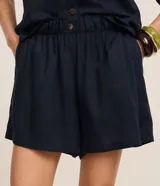 Short runner de viscolino, con cintura elástica, botón decorativo y bolsillos laterales. Presenta un corte evasé holgado con bajo redondeado.